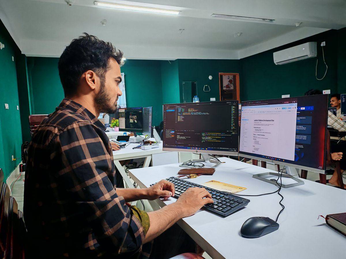 Software developer coding on dual monitors in a modern office